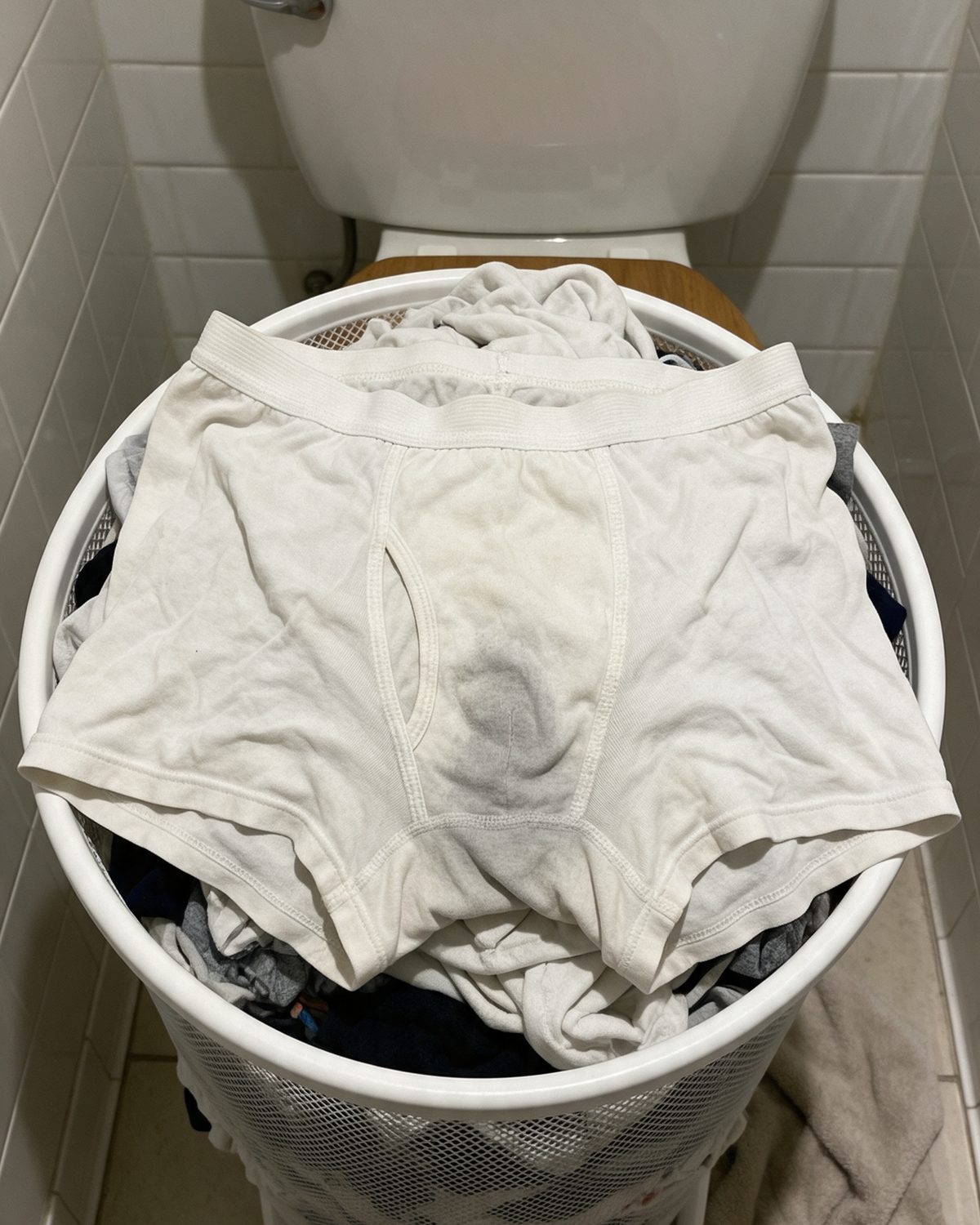 A laundry hamper full of worn-out white cotton underwear